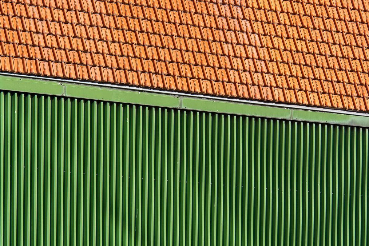 Terracotta roof tiles above green metal siding